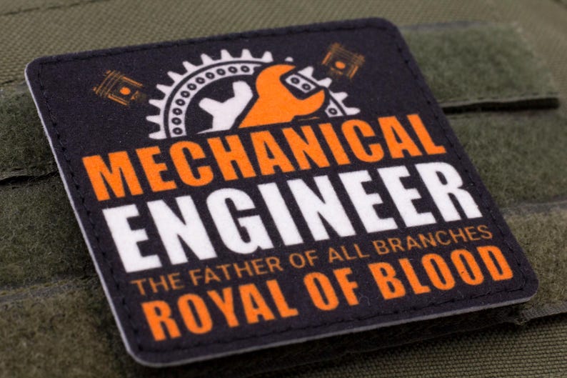Pu&ograve; includere: Toppa quadrata con le parole "MECHANICAL ENGINEER" in bianco e arancione, e il testo "THE FATHER OF ALL BRANCHES ROYAL OF BLOOD". La toppa presenta una chiave inglese, un ingranaggio e un pistone.