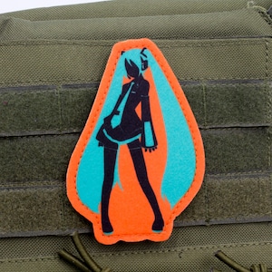 Può includere: Una toppa arancione brillante e turchese con la silhouette di un personaggio femminile di anime con i capelli lunghi. La toppa è progettata per essere applicata a vestiti o una borsa.