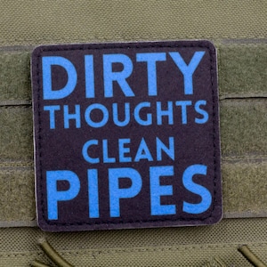 Può includere: Una toppa quadrata con le parole "DIRTY THOUGHTS CLEAN PIPES" in lettere blu su sfondo nero. La toppa è attaccata a un tessuto verde con cinghie in velcro.