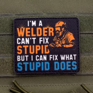 Könnte beinhalten: Ein schwarzer Aufnäher mit dem Text "I'M A WELDER CAN'T FIX STUPID BUT I CAN FIX WHAT STUPID DOES" in Weiß, Orange und Blau. Rechts ist eine Illustration eines Schweißers in Orange. Der Aufnäher befindet sich auf grünem Hintergrund.