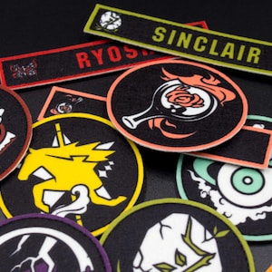 Puede incluir: Una colecci&oacute;n de parches bordados coloridos con varios dise&ntilde;os, incluyendo un caballero, un unicornio, una rosa y un ojo. Los parches est&aacute;n sobre un fondo negro y tienen colores negro, blanco, rojo, amarillo, azul y verde.