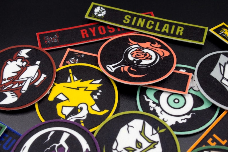 Puede incluir: Una colecci&oacute;n de parches bordados coloridos con varios dise&ntilde;os, incluyendo un caballero, un unicornio, una rosa y un ojo. Los parches est&aacute;n sobre un fondo negro y tienen colores negro, blanco, rojo, amarillo, azul y verde.
