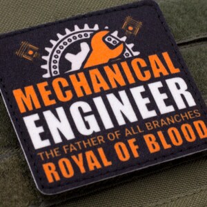 Pu&ograve; includere: Toppa quadrata nera con le parole "MECHANICAL ENGINEER" in arancione e bianco. La toppa presenta un ingranaggio, una chiave inglese e il testo "THE FATHER OF ALL BRANCHES ROYAL OF BLOOD."