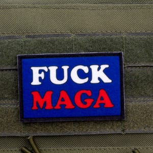May include: A blue patch with white text that says "FUCK" and red text that says "MAGA".