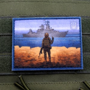 May include: A rectangular patch featuring a watercolor painting of a soldier standing on a beach, facing a warship at sea. The patch has a blue border and is mounted on a green tactical vest. The Ukrainian coat of arms is visible.