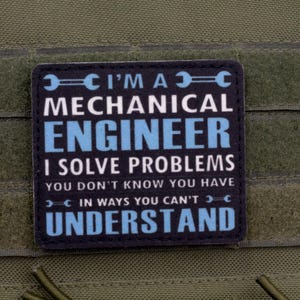 May include: A black and blue patch with the text "I'M A MECHANICAL ENGINEER I SOLVE PROBLEMS YOU DON'T KNOW YOU HAVE IN WAYS YOU CAN'T UNDERSTAND" is attached to a green fabric.