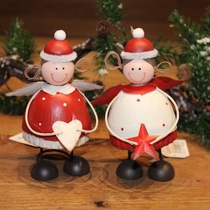 Könnte beinhalten: Zwei rote und weiße Weihnachtsengel aus Metall mit Flügeln. Ein Engel hält ein rotes Herz und der andere einen roten Stern.