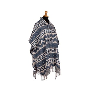 May include: A blue and white patterned poncho with a geometric design. The poncho has a hood, tassels, and fringe along the bottom. The garment is displayed on a mannequin against a white background.