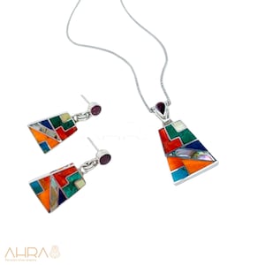 May include: A silver necklace and earrings set with a geometric pendant and matching earrings. The pendant and earrings are made of silver and feature a colorful mosaic of stones, including turquoise, coral, and mother-of-pearl.