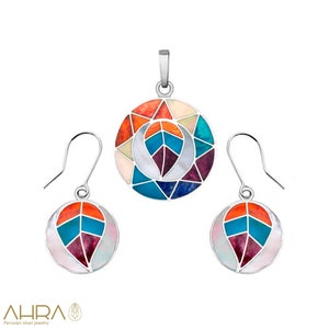 May include: A silver pendant and earrings set with a colorful geometric design. The pendant and earrings feature a leaf shape with a white center and a multi-colored mosaic pattern.