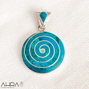May include: A silver pendant with a turquoise blue spiral design. The pendant is round and has a small teardrop-shaped turquoise stone at the top.