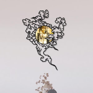 May include: A black metal wall mirror with a circular design featuring a cloud-like pattern. The mirror is reflecting a room with a white wall and a table with chairs.