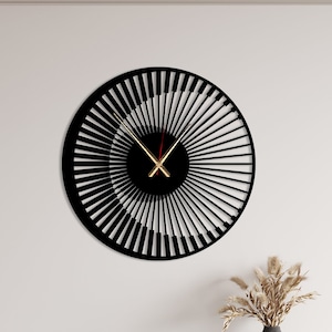 Może przedstawiać: Czarno-biały zegar o unikalnym designie, przedstawiający spiralę z klawiszami fortepianu. Zegar ma złote wskazówki i jest zamontowany na białej ścianie.