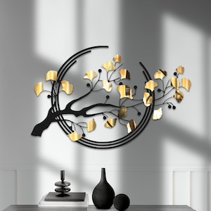 May include: Black metal wall art featuring a stylized tree branch with gold leaf accents. The branch is curved into a circle shape and is mounted on a white wall above a black console table.