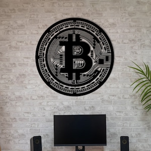 Puede incluir: Decoración de pared de metal negro con un diseño circular que presenta un símbolo de Bitcoin y código binario. La decoración está montada en una pared de ladrillo blanco sobre un escritorio negro con un monitor de computadora, teclado y dos altavoces negros.