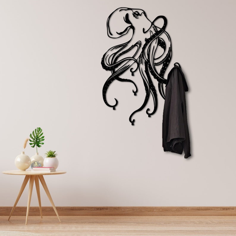 May include: Black metal octopus wall hook with a coat hanging on one of the tentacles. The octopus is stylized with a detailed design.