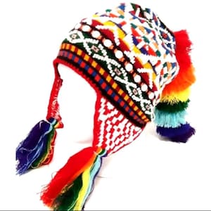 May include: A colorful knit hat with ear flaps and a tassel. The hat features a geometric pattern in red, white, yellow, blue, and green. The ear flaps and tassel are adorned with rainbow-colored strands. The hat is designed to keep the head warm.