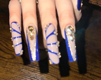 May include: Long, blue and nude acrylic nails with intricate designs and rhinestones.