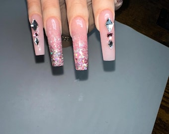May include: Long, pink, glitter-tipped acrylic nails with rhinestones.