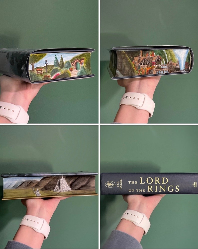 Pu&ograve; includere: Una copia con copertina rigida di The Lord of the Rings di J.R.R. Tolkien con copertine nere e scritte dorate. I bordi delle pagine presentano scene dipinte a mano, tra cui un paesaggio verde con una porta rotonda, un edificio e delle cascate.