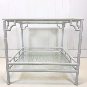 May include: A light gray bamboo-style side table with two glass shelves. The table has a rectangular top and a lower shelf, both made of clear glass. The frame is painted a light gray color, and the design features decorative cutouts.
