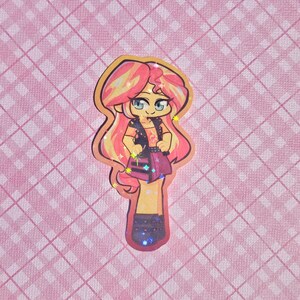 May include: A colorful sticker featuring a cartoon character with pink and yellow hair, blue eyes, and a black vest. The character is wearing a pink skirt and black boots. The background is a pink plaid pattern.