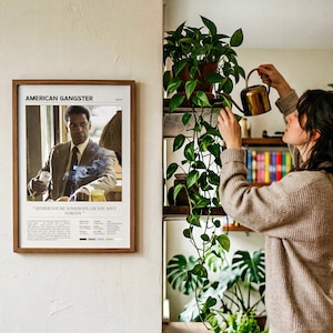 American Gangster poster, Light edition, framed and on the wall beside someone watering the plants