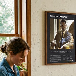 American Gangster poster, Dark edition, framed and on the wall beside someone repotting a plant