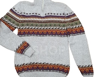 Può includere: Un maglione grigio chiaro con zip e lavorazione a maglia strutturata. Il maglione presenta un colorato motivo geometrico sul petto e sulle maniche, con disegni marroni, arancioni, viola e bianchi. Il colletto è a collo alto.