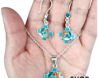 Può includere: Un set di collana e orecchini in argento con un ciondolo a forma di croce e orecchini abbinati. I gioielli hanno intarsi turchesi, arancioni, verdi e gialli. Il testo "SHOP PERU" è visibile.