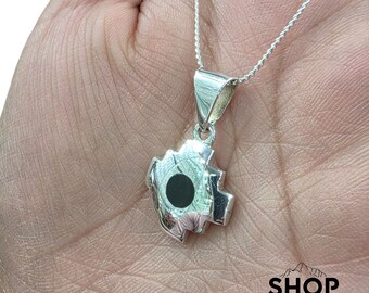 Può includere: Una collana con pendente in argento con un design stilizzato unico con un cerchio nero centrale. Il pendente è appeso a una sottile catena d'argento. L'immagine include il testo "SHOP PERU" in basso a destra.