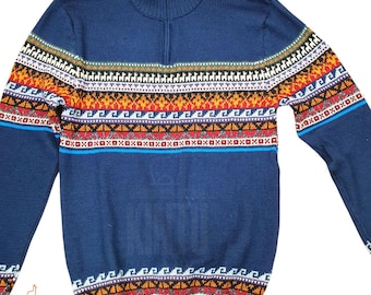 Può includere: Un maglione blu navy con collo alto e chiusura con zip a un quarto. Il maglione presenta un colorato motivo geometrico in rosso, arancione, bianco e nero sul petto e sulle maniche. Il logo del marchio "KINTU" è visibile in basso a sinistra.