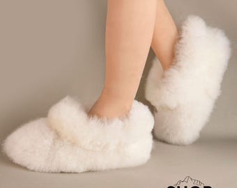 Può includere: Ciabatte bianche in morbida lana di alpaca. Le ciabatte sono morbide e confortevoli, perfette per tenere i piedi al caldo in inverno.