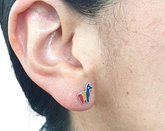 Può includere: Un orecchino a lobo in argento con un colorato design a lama. La lama è raffigurata con smalto rosso, giallo e blu, creando un accessorio vivace. L'orecchino è mostrato su un orecchio.