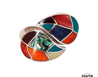 Può includere: Un anello d'argento con un design geometrico colorato. L'anello è composto da due pezzi che sono uniti insieme. Il design presenta una varietà di colori, tra cui rosso, arancione, giallo, verde, blu e viola.