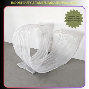 Może przedstawiać: Biała, przezroczysta struktura z tkaniny, być może zasłona lub element dekoracyjny, ułożona w pętlę, płynny wzór. Tekst na zdjęciu wskazuje na różne rozmiary, krawędzie druciane/surowe oraz pojedyncze/podwójne warstwy. Ogólna estetyka jest minimalistyczna i przewiewna.