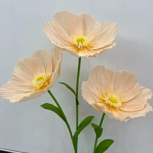 Peut inclure: Trois grandes fleurs artificielles avec des p&eacute;tales couleur p&ecirc;che et des centres jaunes. Les fleurs ont des tiges et des feuilles vertes. Les p&eacute;tales ont un aspect textur&eacute;. Les fleurs sont probablement &agrave; des fins d&eacute;coratives.