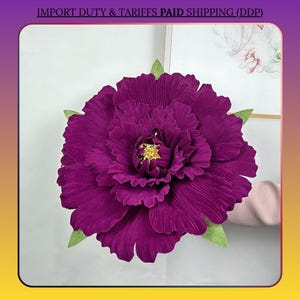 Può includere: Un grande fiore di peonia artificiale viola scuro con foglie verdi. Il fiore ha un design a petali dettagliato e stratificato e un centro giallo dorato. L'immagine include il testo "IMPORT DUTY & TARIFFS PAID SHIPPING (DDP)".