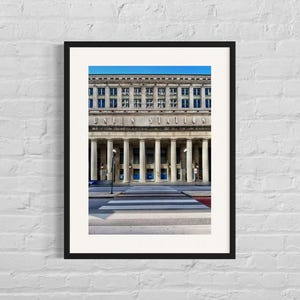 May include: A black and white photograph of Union Station in Chicago. The building has a large, ornate facade with columns and a sign that reads "Union Station". The photo was taken from street level, looking up at the building.