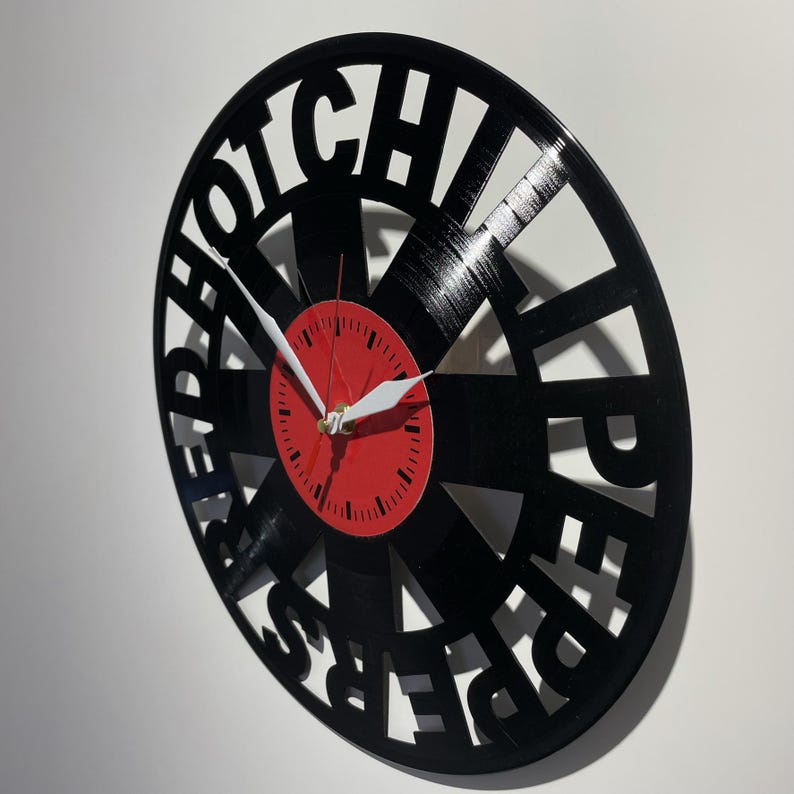 May include: A black vinyl record clock with the words "HOTCHILIPEPPERS" cut out around the edge. The clock face is red with white hands.