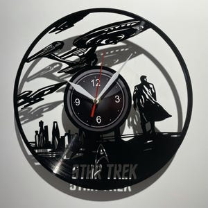 May include: A black vinyl record clock featuring a silhouette of the Starship Enterprise from Star Trek, a figure in a cloak, and the text "STAR TREK".