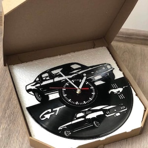 May include: A black vinyl record clock featuring a silhouette of a Ford Mustang GT. The clock is packaged in a cardboard box with foam padding.