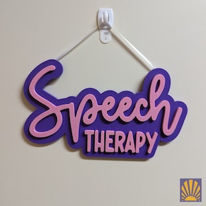 May include: A wall-mounted sign featuring the words Speech Therapy in a layered design. The word Speech is in a pink cursive script, while the word Therapy is in pink block letters. Both are set against a dark purple backing board.
