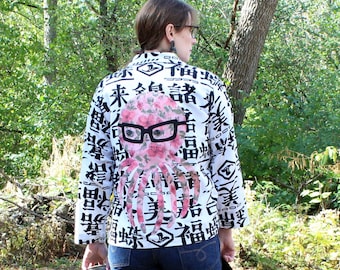 May include: A white long-sleeve button-down shirt featuring a repeating black Japanese kanji character pattern and a large, central pink floral-print octopus graphic wearing black-rimmed glasses on the back of the garment.