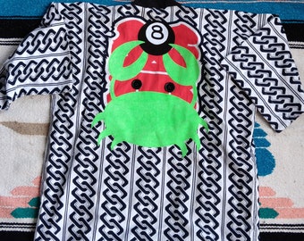 May include: A white and black jacket featuring a repeating chain-link pattern. The back displays a large graphic of a red crab with a black and white number eight billiard ball on its back, accented with bright green claws and a green body.