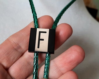 vintage F bolo tie, initial letter by Swank, silver and black on metallic green braided rope