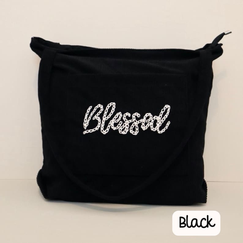 Black corduroy Christian tote bag with zipper and large front pocket, handmade with embroidered scripture design. Perfect for Bible study, church, school, or everyday use. Durable and stylish women’s Bible bag, ideal as a gift for faith-driven book lovers or anyone seeking a functional, faith-inspired tote. Chain stitch font embroidery text Blessed teacher tote bag.