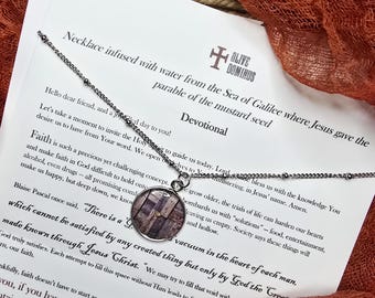 May include: A silver-toned necklace with a round pendant featuring a wood grain design. The pendant hangs from a delicate chain. The necklace is displayed on a printed devotional card with text.