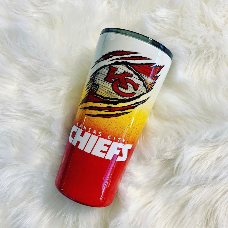 K&ouml;nnte beinhalten: Ein roter, gelber und wei&szlig;er Edelstahlbecher mit einem Kansas City Chiefs Logo. Das Logo zeigt ein rotes "K" &uuml;ber einem wei&szlig;en "C" mit einem gelben und roten Hintergrund. Die Worte "Kansas City Chiefs" sind unter dem Logo aufgedruckt.