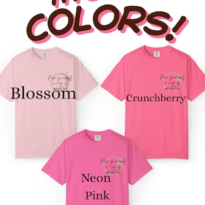 May include: Three short-sleeve t-shirts in shades of light pink, medium pink, and neon pink. Each shirt features a small graphic on the left chest with a coffee ring stain and the text "Pour yourself a cup of ambition." Text labels read "Blossom," "Crunchberry," and "Neon Pink."